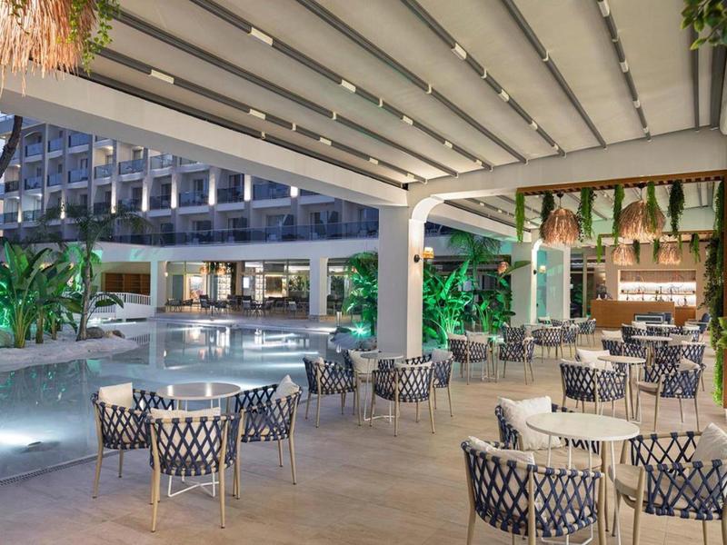 Espace extérieur d'hôtel moderne avec piscine, sièges et éclairage d'ambiance.