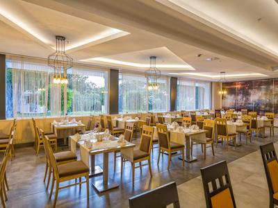 Jasna, nowoczesna restauracja hotelowa z drewnianymi krzesłami, stołami i dużymi oknami.