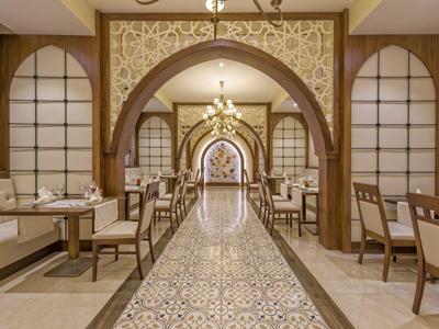 Elegancki hotelowy korytarz z ozdobnymi łukami, dekoracyjną mozaikową podłogą i miejscami do siedzenia.