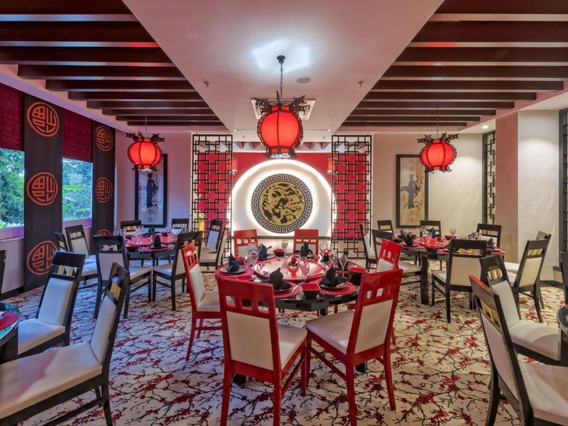 Elegantes Restaurant mit asiatischem Stil, roter Dekoration und rundem Wandkunstwerk.