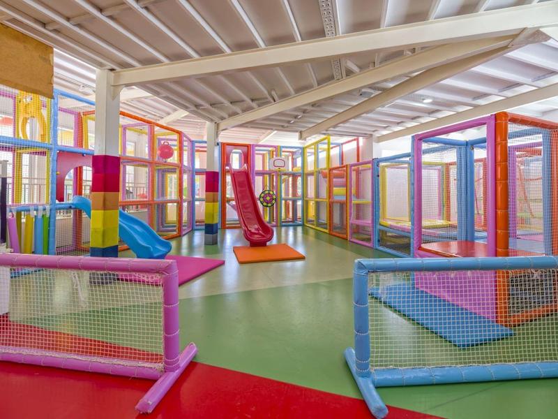 Buntes Indoor-Spielplatz mit Rutschen, Kletterstrukturen und weichen Matten in großen Raum.