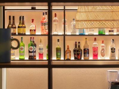 Plank met verschillende flessen alcoholische dranken en glazen in een bar.