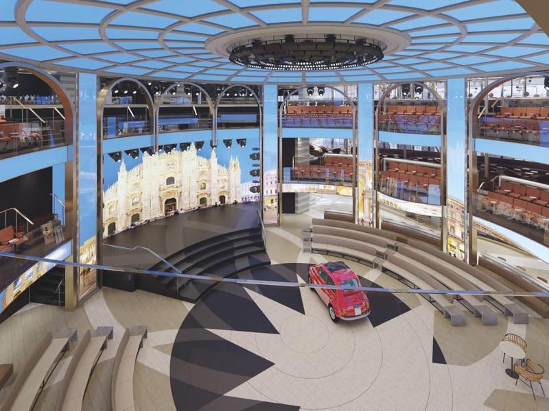 Anfiteatro moderno al aire libre con filas de asientos claros y un coche rojo en el suelo central con patrón.