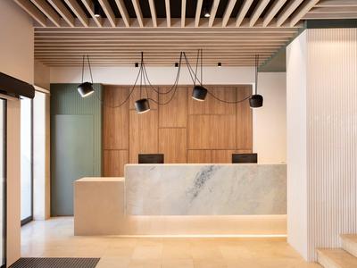 Recepción moderna de hotel con mostrador de mármol, pared de madera y lámparas colgantes en estilo minimalista