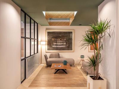 Cozy seating area with sofa, wooden floor, and large plant, illuminated by skylight.