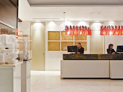 Réception d'hôtel moderne avec comptoir et lampes rouges décoratives au plafond.