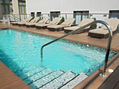 Kleiner Pool mit Treppe und Handlauf, umgeben von Liegestühlen auf Holzterrasse.