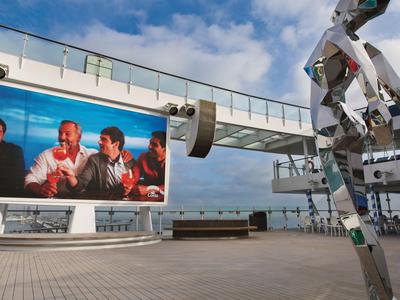 Large outdoor screen on a terrace with seating and a metallic structure.