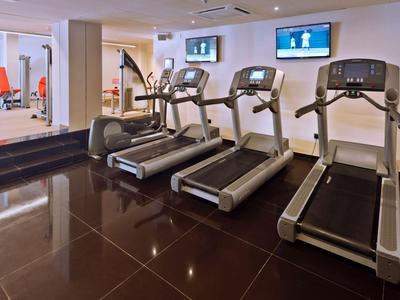 Moderner Fitnessraum mit drei Laufbändern und Fernsehern an der Wand