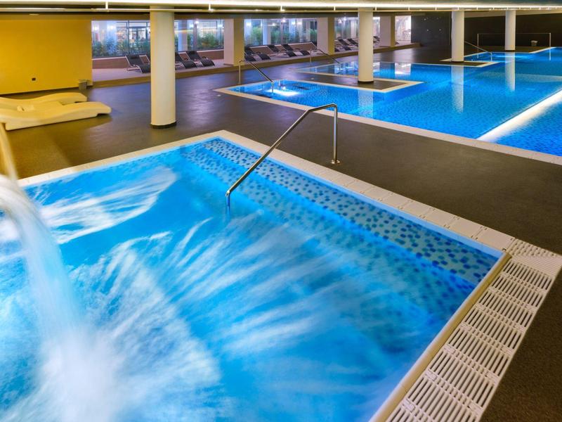 Area spa interna con jacuzzi, giochi d'acqua e piscina grande.