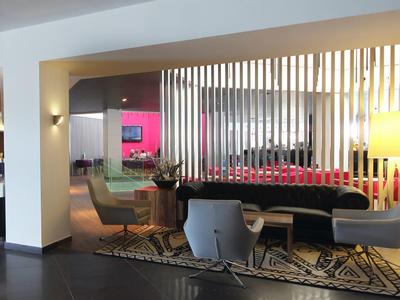 Modern hotel lobby seating area with chairs, table, carpet, and ambient lighting.