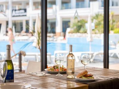Table with wine bottles and glasses overlooking a pool area with sun loungers.