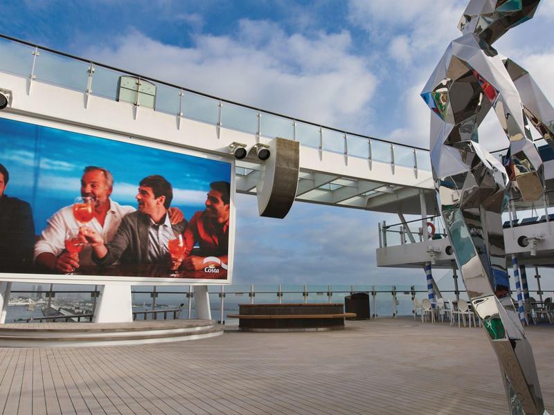 Outdoor terrace with screen and modern sculpture under blue sky in hotel area