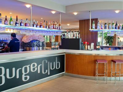 Modern bar area with bottles on shelves and stools at the counter in a hospitality setting.