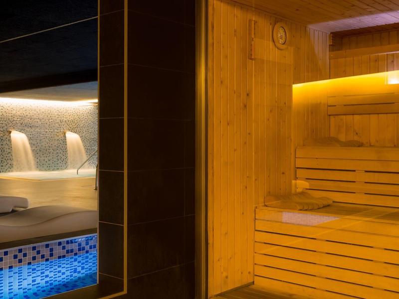 Modern sauna with wooden benches and adjacent pool with water jets