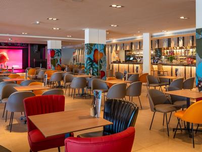 Area lounge moderna dell'hotel con sedie colorate e grande bar sullo sfondo
