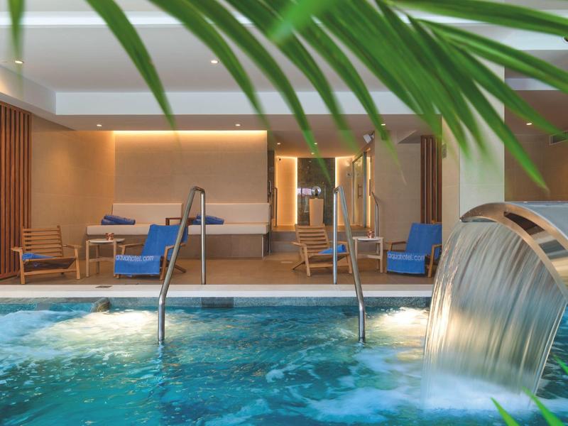 Innenpool mit Wasserfall und Sitzbereich in modernem Spa-Hotel