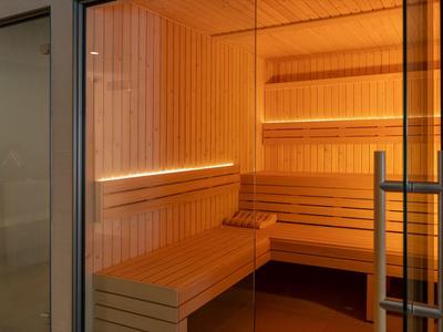 Helle Holzsauna mit mehrstufigen Holzliegen und indirekter Beleuchtung.