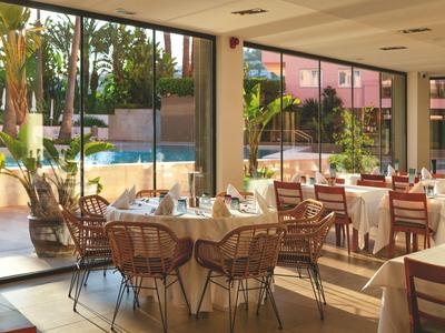 Heller Speisesaal mit gedeckten Tischen und Sicht auf den Pool durch große Fenster