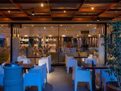 Ristorante accogliente con illuminazione calda, tavoli apparecchiati e piante interne.