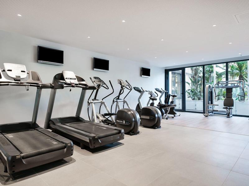 Palestra moderna in hotel con tapis roulant, ellittiche e grandi finestre con vista esterna.