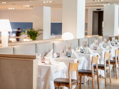 Modernes Restaurant mit weißen Tischdecken, Holzstühlen und warmem Lampenlicht.