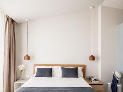 Minimalist bedroom with white wall, double bed, and two bedside tables.