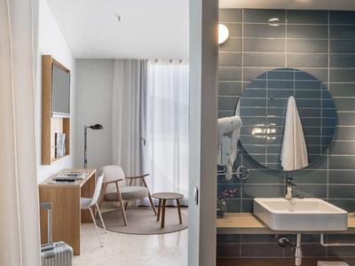 Moderne hotelkamer met kamerscherm, badkamer met donkerblauwe tegels en woonruimte erachter