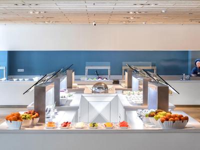 Buffet moderno con frutta e prodotti per la colazione in un'area pranzo luminosa.