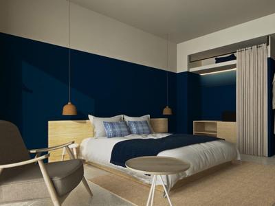 Modern hotel room with a large bed, navy blue wall, and stylish wooden furniture.