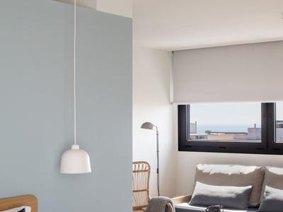 Modern hotel room with a cozy sitting area and a hanging lamp by the bed.