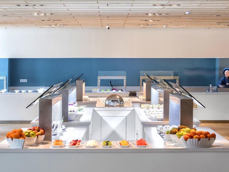 Modern buffet setup with fruits and breakfast items in a bright dining area.