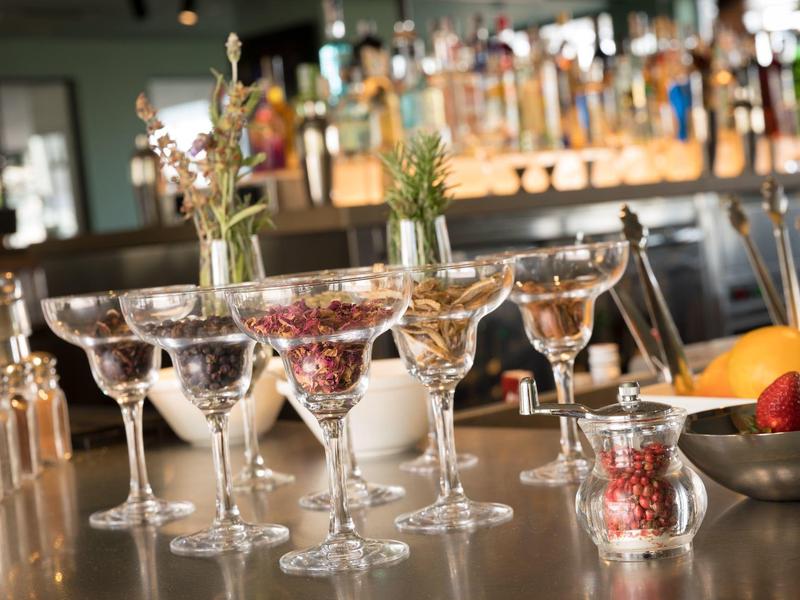 Cocktail glasses filled with colorful ingredients on a bar counter.