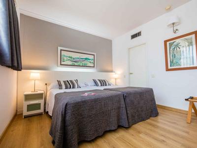 Modern eingerichtetes Hotelzimmer mit Doppelbett, Holzfußboden und dekorativen Bildern an der Wand.