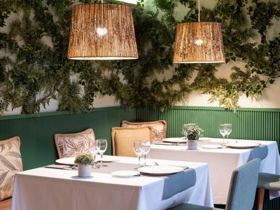 Accogliente zona pranzo con tovaglie, piante e lampade sospese calde in un hotel