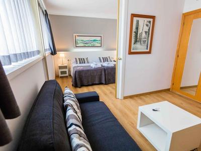 Modern eingerichtetes Hotelzimmer mit Doppelbett, Sofa und Holzboden.