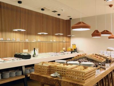 Modern breakfast buffet with baskets of bread, drinks, and wooden wall panels in a bright dining area.