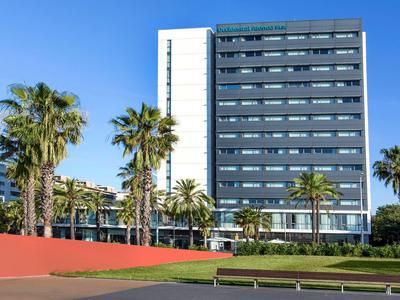 Tall modern hotel building with palm trees and clear blue sky