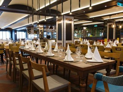 Restaurant moderne avec tables en bois dressées et serviettes blanches pliées.