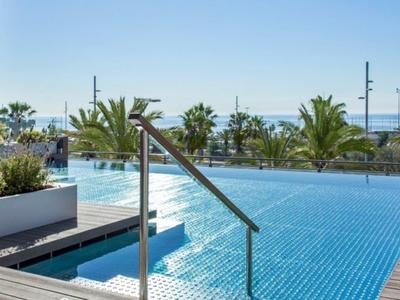 Piscina esterna moderna con vista mare e palme in un resort.