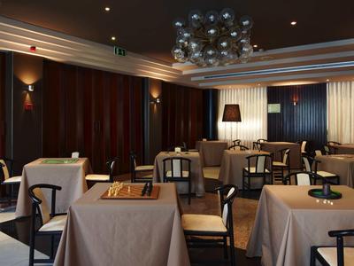 Elegantes Restaurant mit gedeckten Tischen, dunklen Wänden und moderner Deckenbeleuchtung.