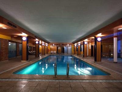 Beheiztes Hallenbad mit heller Beleuchtung, breitem Einstieg und glatter Wasseroberfläche.