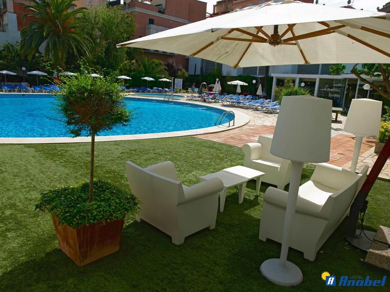 Pool mit runden Form, weißem Sonnenschirm, modernen weißen Sesseln und grünem Pflanzenkoffer.