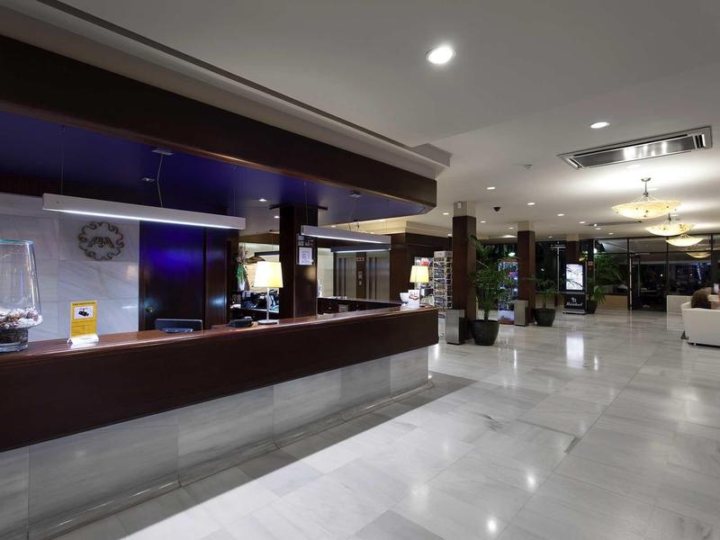 Großer, moderner Empfangsbereich mit dunklem Empfangstresen und hellem Marmorboden.