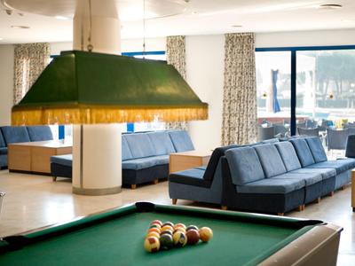 Billardtisch mit blauer Couchlandschaft und großen Fenstern im Hintergrund