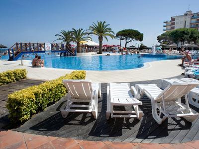 Piscina redonda del hotel con tumbonas, sombrillas y palmeras en un día soleado.