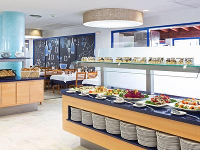 Moderno restaurante de hotel con buffet y varios platos organizados en mesas.