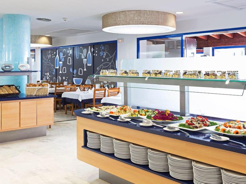 Moderno restaurante de hotel con buffet y varios platos organizados en mesas.