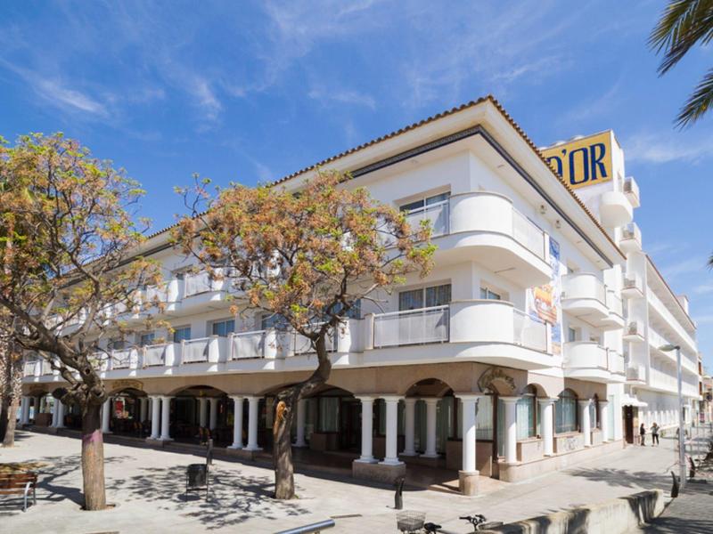 Edificio hotelero moderno blanco con balcones bajo un cielo azul a la luz del día.