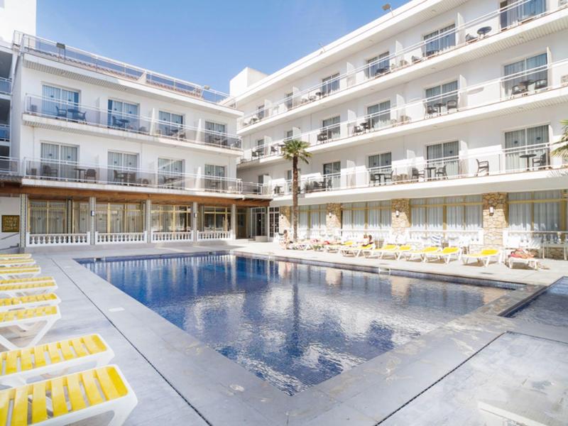 Área moderna de piscina de hotel con tumbonas y varios pisos con balcones.
